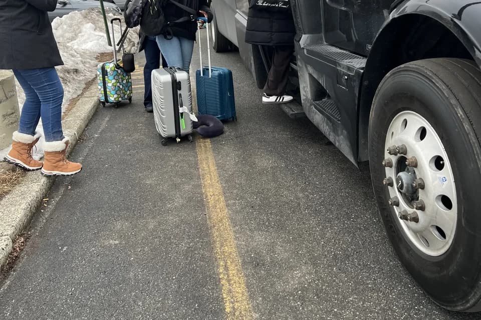 Group of passengers loading luggage onto an AZA motorcoach