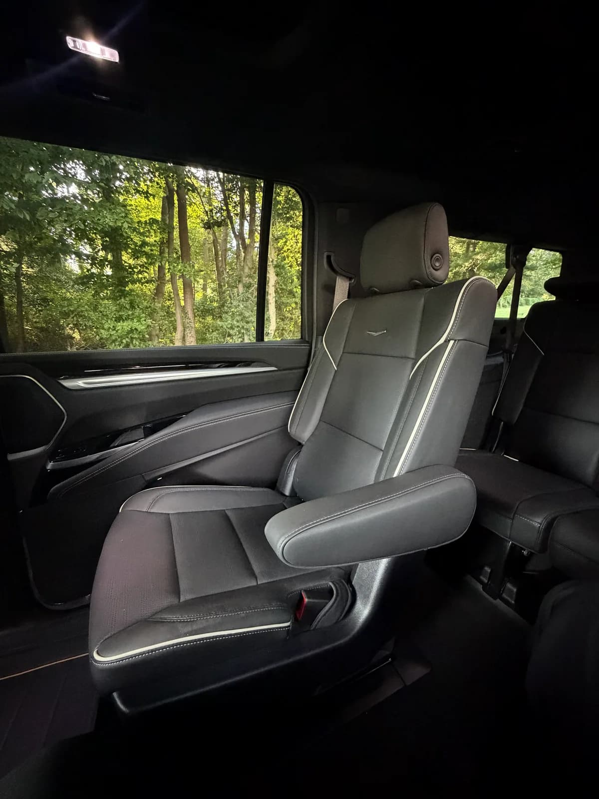Captain's chair inside an AZA Cadillac Escalade with trees visible through the window