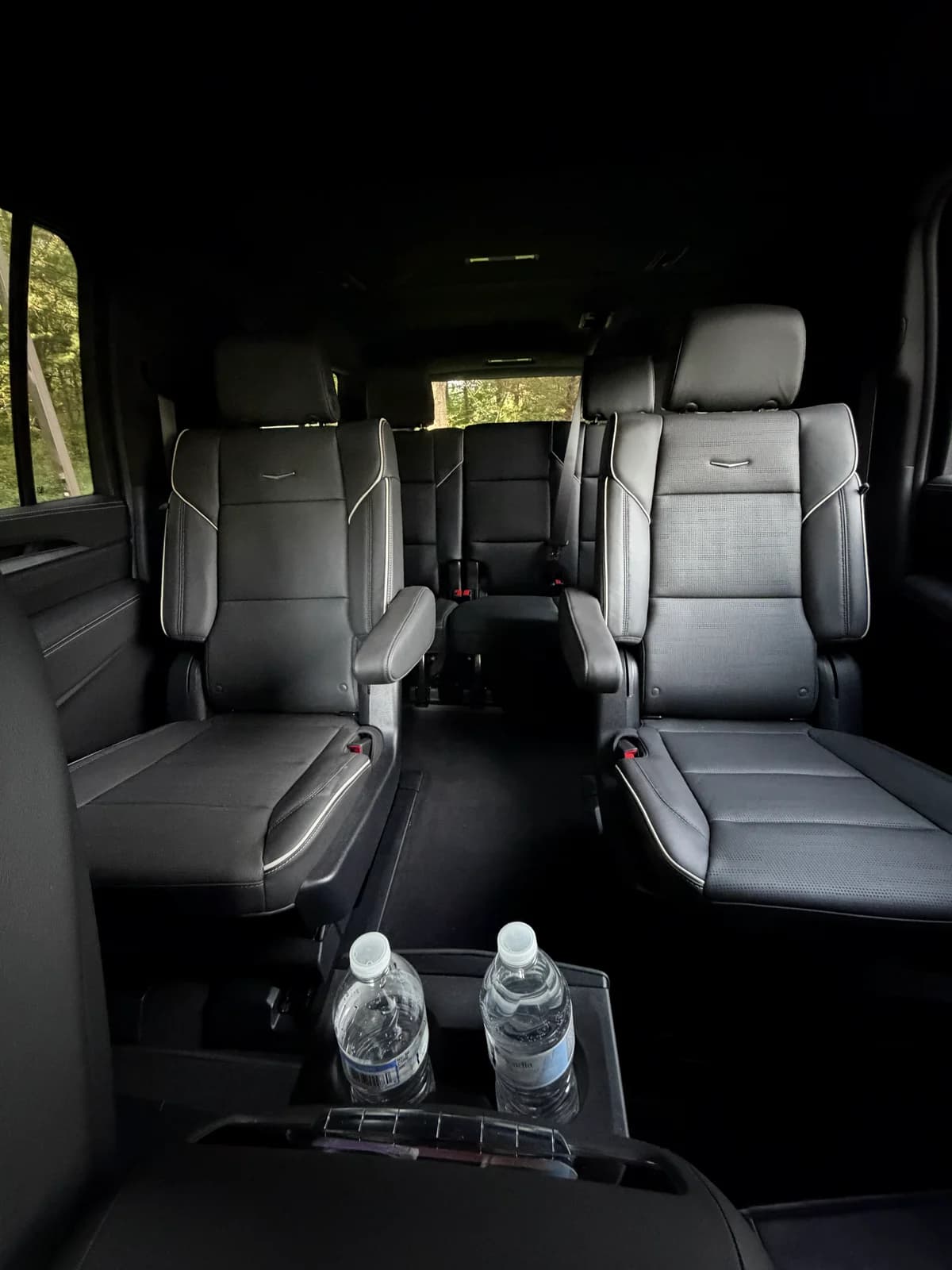 Second-row captain's chairs and bottled water inside an AZA Cadillac Escalade