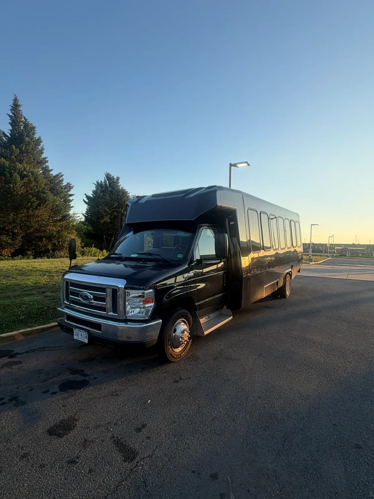 AZA Ford E450 shuttle bus parked beside trees