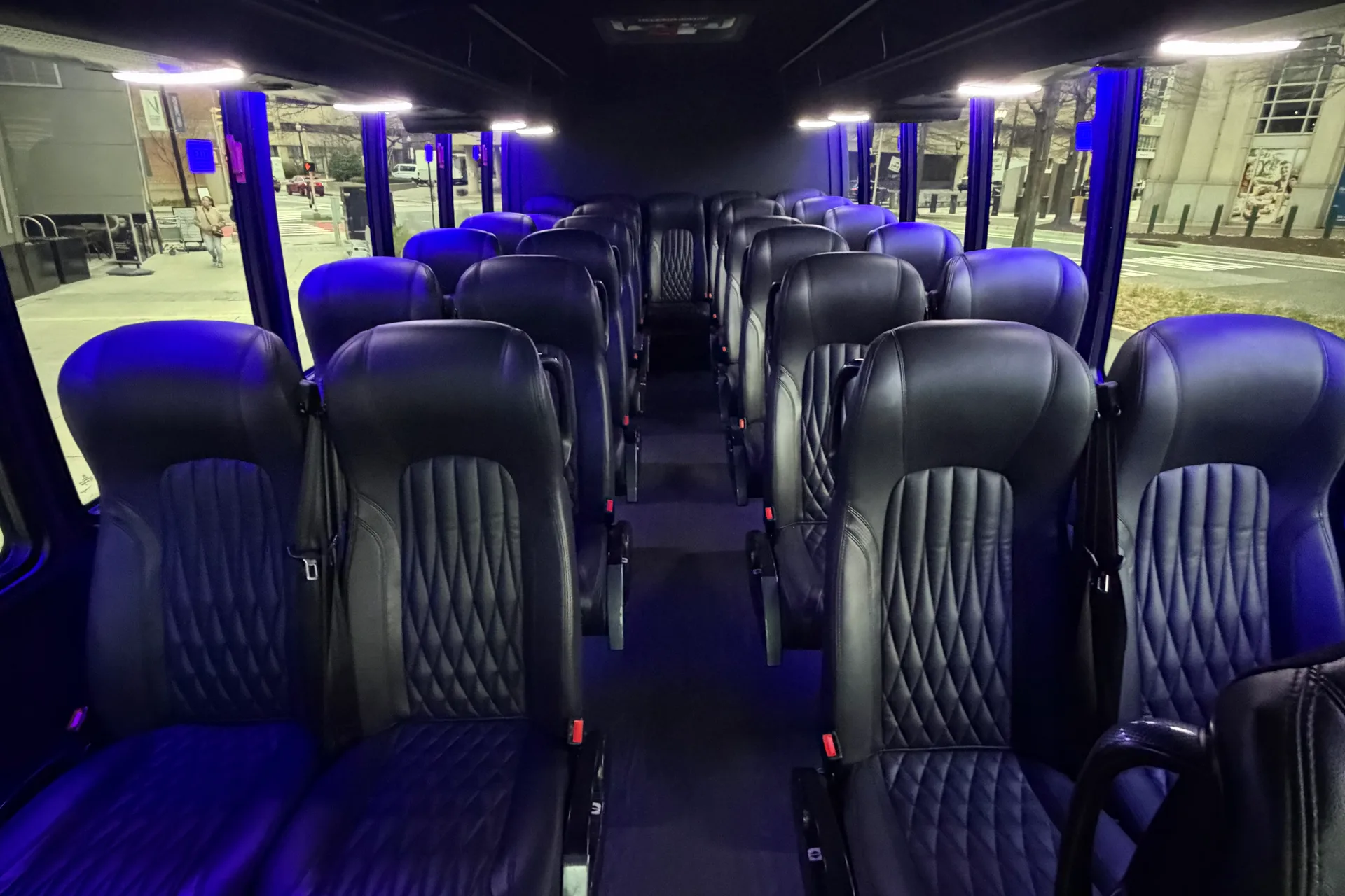 Interior of an AZA Mini Party Bus with rows of seating under blue accent lighting