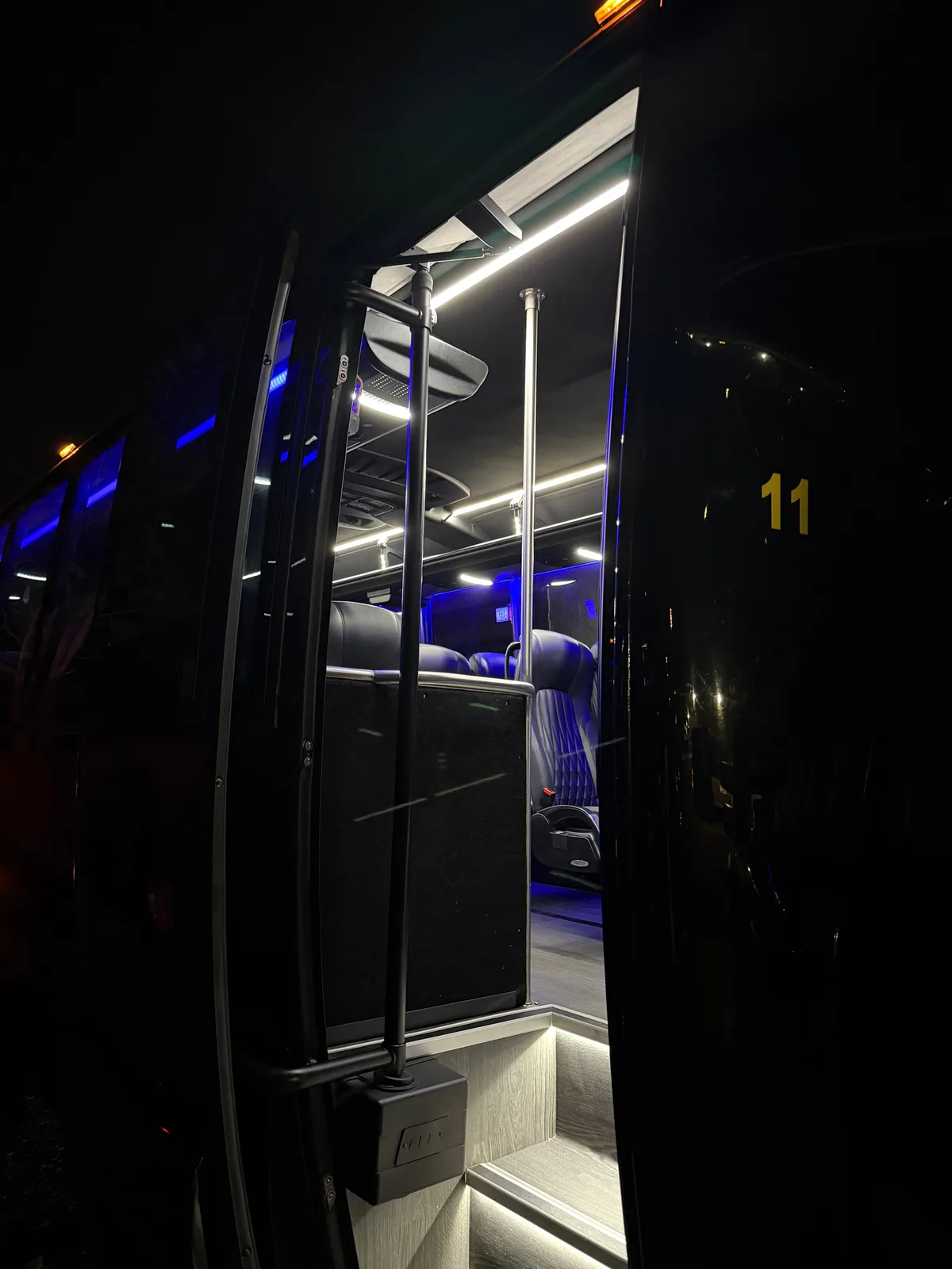 Boarding stairwell of an AZA Mini Party Bus lit with blue accent lighting at night