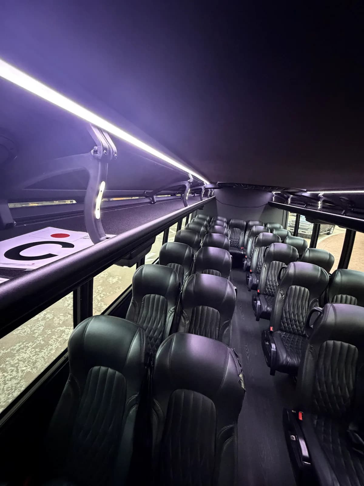 Rows of seating under purple LED lighting inside the AZA GM40 bus at night