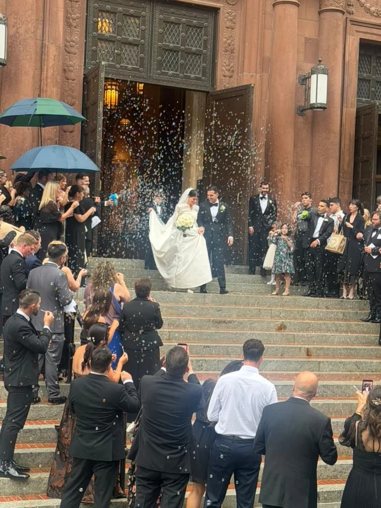 Bride and groom exiting the church through confetti, AZA wedding transportation waiting